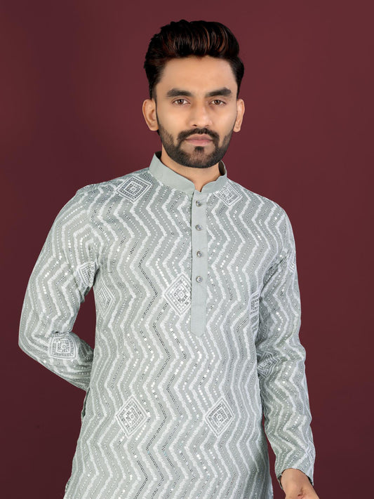 Man wearing a light gray patterned kurta against a maroon background