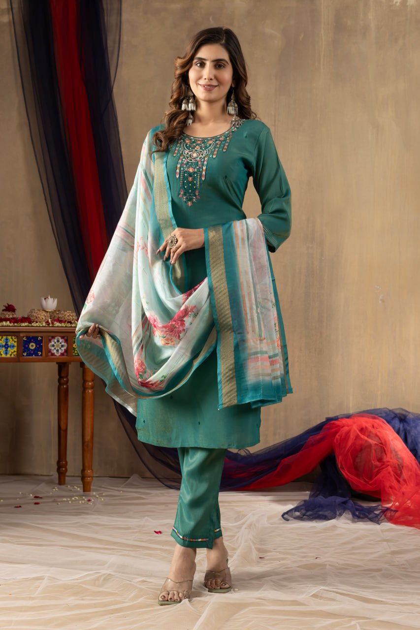 Woman in a teal traditional outfit with a colorful dupatta against a neutral background