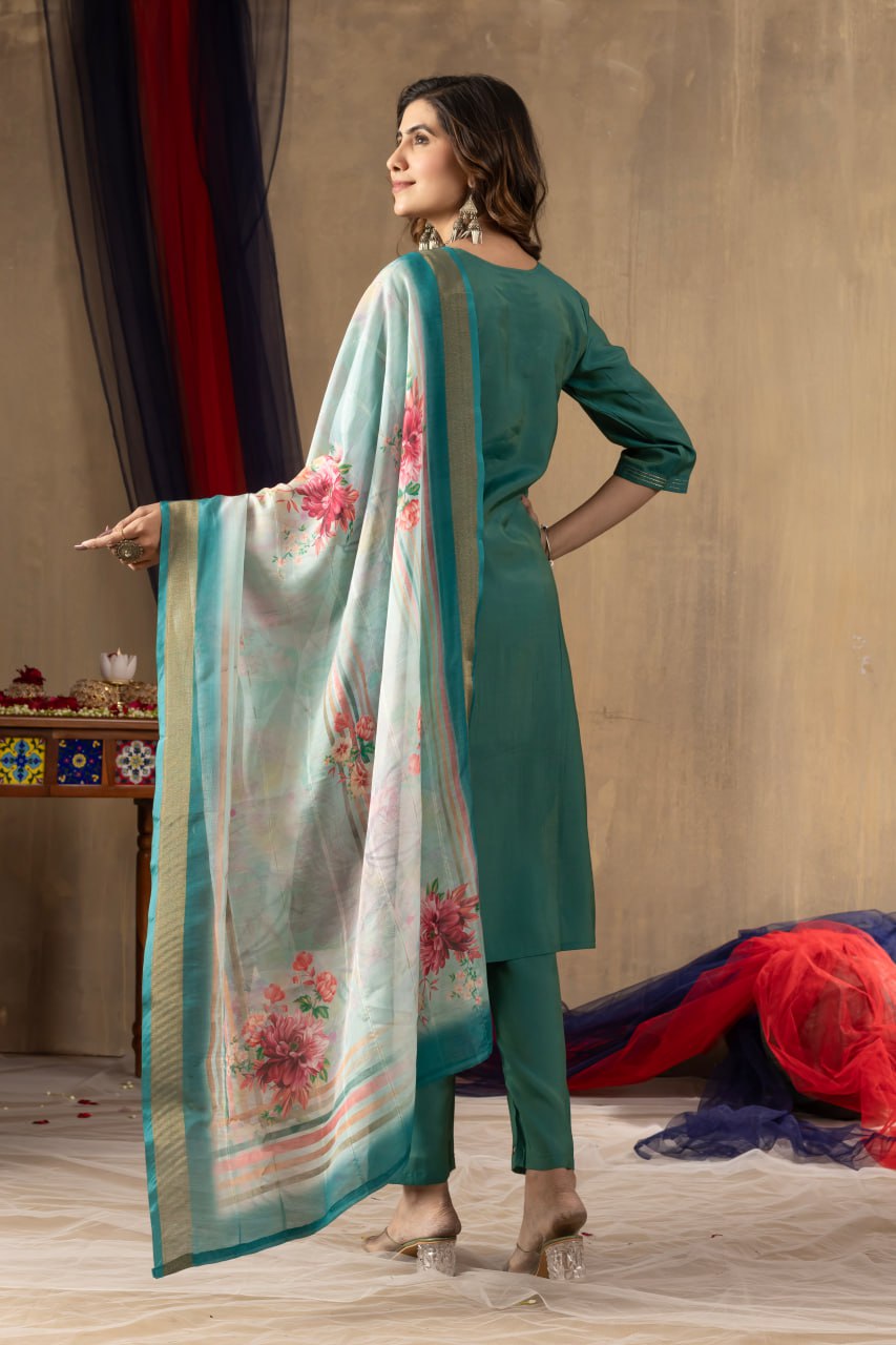 Woman in teal outfit with floral dupatta against a neutral background