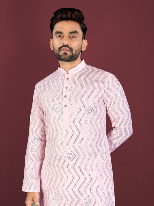 Man wearing a light pink kurta with white patterns against a dark red background