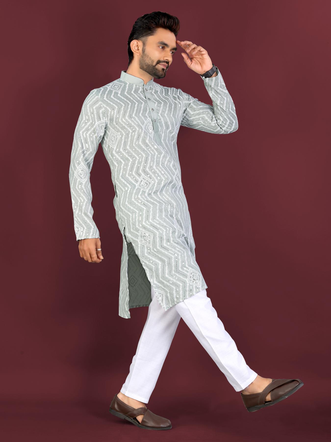 Man wearing a light gray kurta with white pants on a dark red background