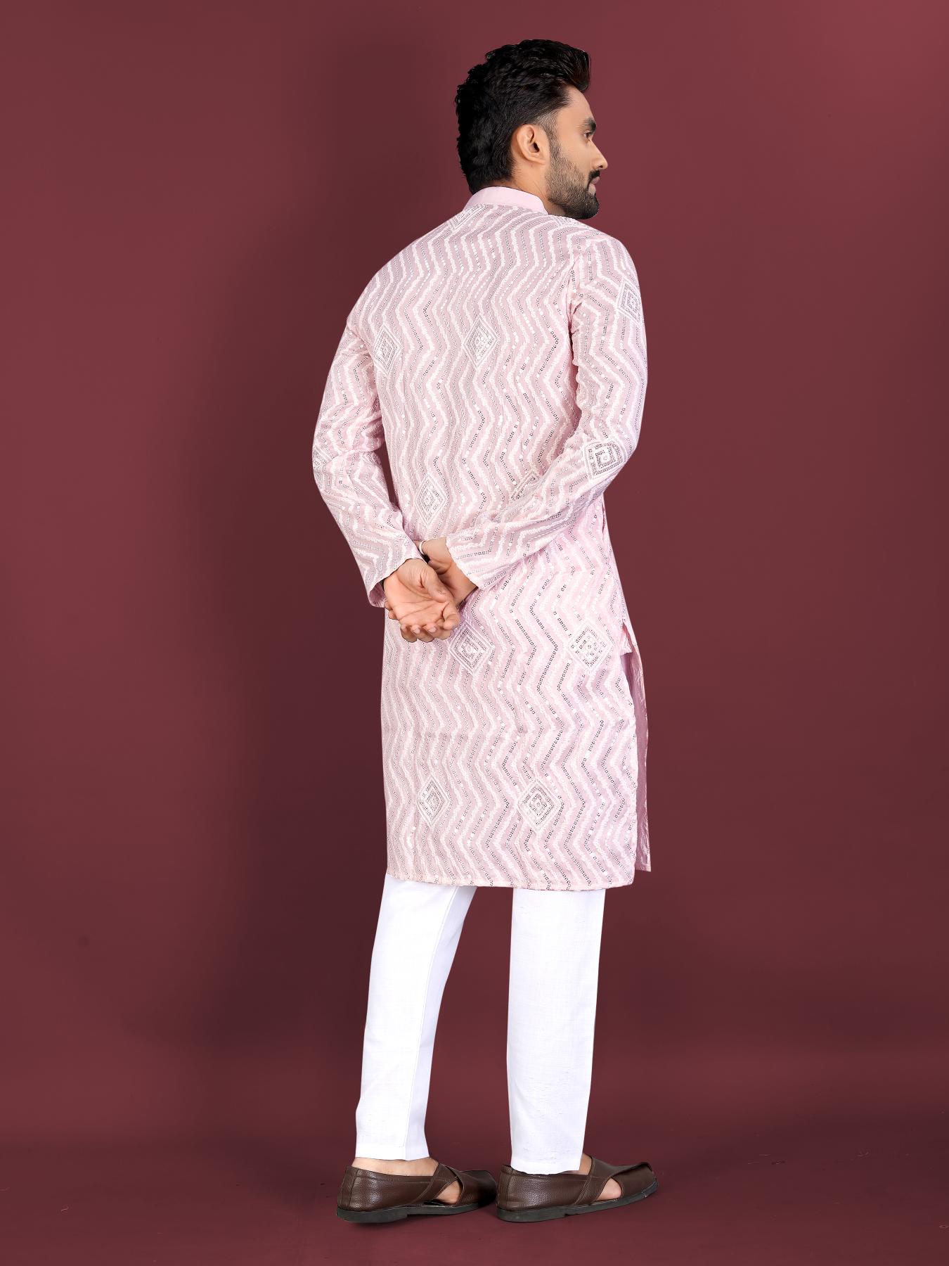 Man wearing a light pink kurta with white pants on a maroon background