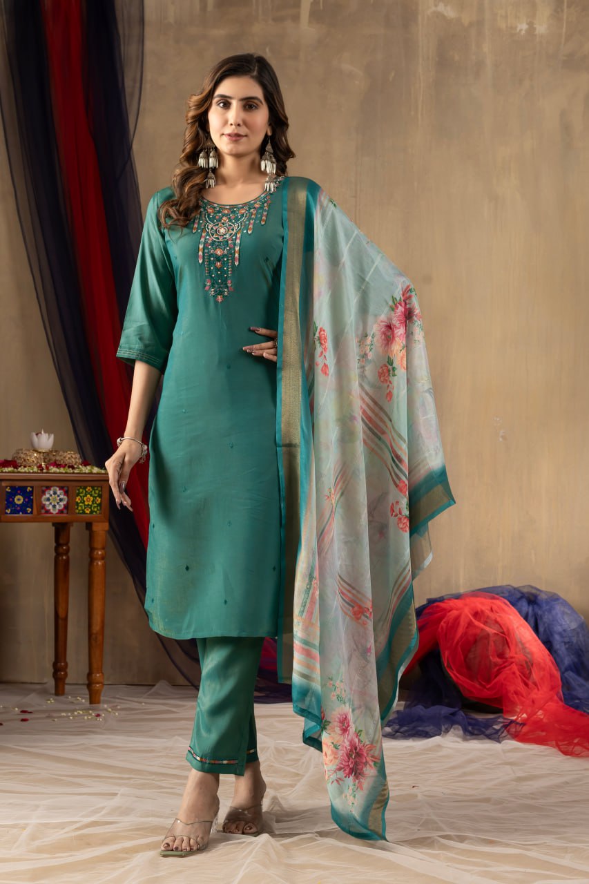 Woman in teal traditional outfit with floral dupatta against a neutral background