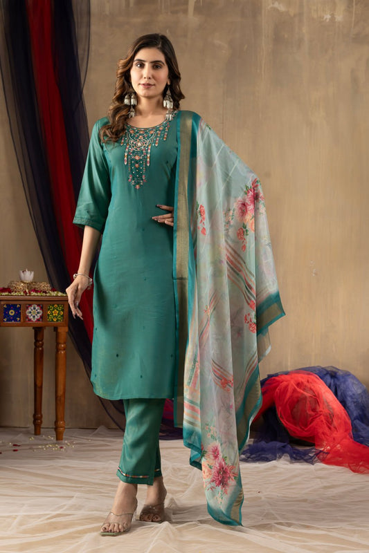 Woman in teal traditional outfit with floral dupatta against a neutral background